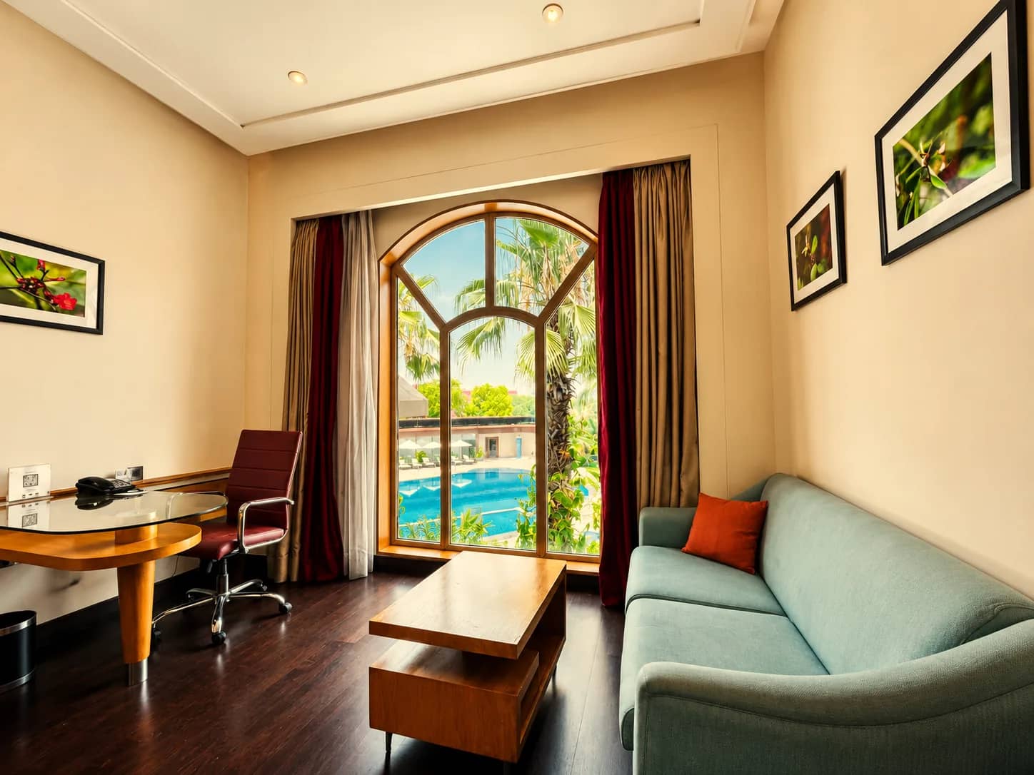 Sitting area and desk by the arched window overlooking the pool